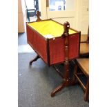 A George IV mahogany cot bed, externally close studded upholstered in red cloth and swinging between