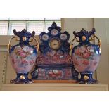 A late Victorian/Edwardian clock garniture, boldly decorated with pink roses and primroses on a