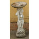 A reconstituted stone bird bath, the dished top on a column fashioned as a putto holding a