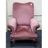 A George II style oak framed and dusky pink velour upholstered armchair, having saddle back rolled