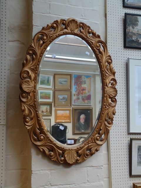 A reproduction giltwood framed oval wall mirror with bevelled plate