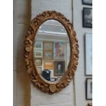 A reproduction giltwood framed oval wall mirror with bevelled plate