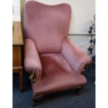 A George II style oak framed and dusky pink velour upholstered armchair, having saddle back rolled