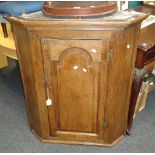 An early 19th century oak wall mounting corner cupboard, with a fielded arched panelled door