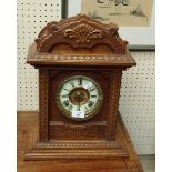 An early 20th century Ansonia 8 day mantel clock, with carved oak architectural case, together