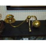 An Arts and Crafts design brass candle holder, with scrolling single arm and loaded sphere counter