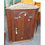 A small late 18th century oak wall mounting corner cupboard, with arched moulded door enclosing