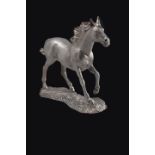 A filled silver model of a cantering horse, realistically modelled on grassy plinth, with