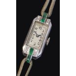 An Art Deco emerald and diamond cocktail watch, rectangular with four stone diamond shoulders and