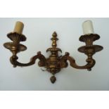 A pair of gilt brass George II style two sconce wall lights, with flambe finials