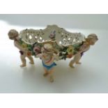 A 19th century Continental porcelain table centre piece, fashioned as four putti supporting a