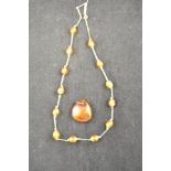 An amber pendant - 2.7x2.7cm, together with a thirteen bead amber necklace mounted in yellow