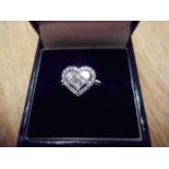 An 18ct white gold ring with three diamonds to centre forming a heart, surrounded by twenty two