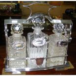 A silver plated tantalus complete with three decanters and five assorted spirit labels