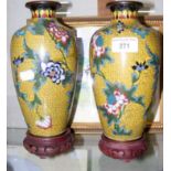 A pair of decorative cloisonne vases on wooden stands