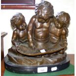 A bronze group of three putti reading a scroll - 28cm high with marble base