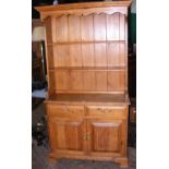 A stripped pine dresser with two drawers to the apron, cupboards below enclosed by panelled