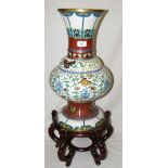 A Chinese cloisonne vase with butterfly and scroll design and ornate shaped hardwood base - 72cm