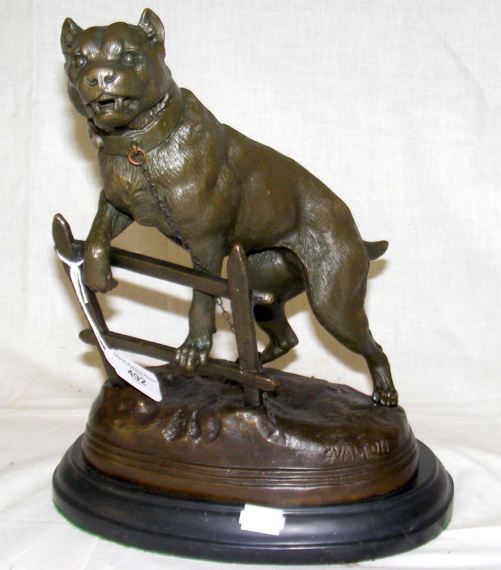 A reproduction bronze figure of a fierce dog up on a fence - stamped C Valton - 30cm high overall