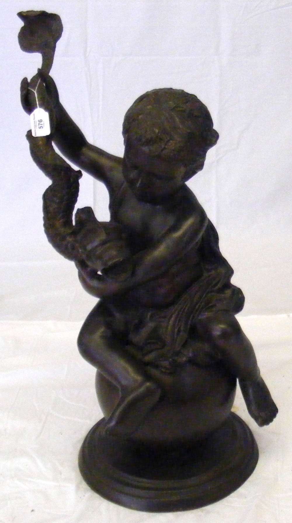 A bronze figure of a cherub seated on a globe and holding a stylized dolphin - 79cm high overall