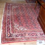 A Middle Eastern style carpet with red ground and geometric border - 310cm x 216cm