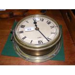 An old ship's brass cased bulkhead clock - 22cm diameter