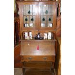 An Arts and Crafts oak bureau bookcase with lead glazed doors to the top