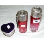 Two continental cranberry glass silver top cologne bottles and an embossed silver heart shaped
