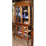 An Edwardian display cabinet with cross banded doors and break-front base