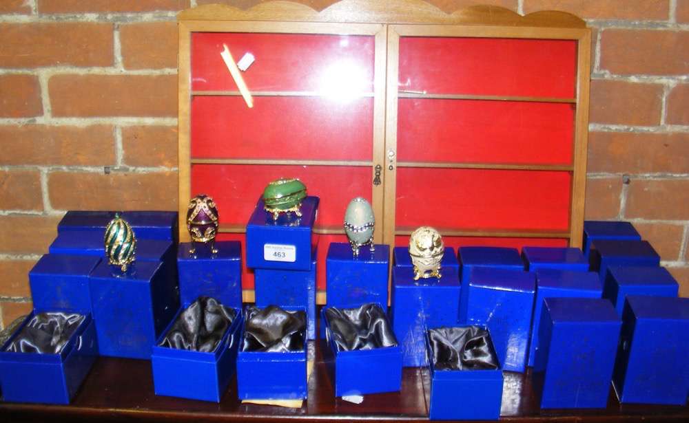 Quantity of boxed Faberge style eggs on stands with display case