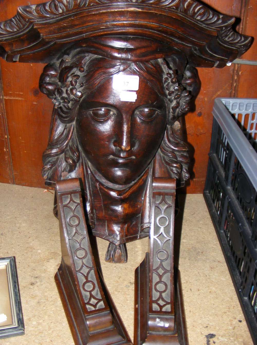 An ornately carved hardwood wall bracket in the form of a classical female head and a pair of