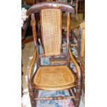 An antique rocking chair with cane work seat and backrest