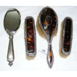 A four piece tortoiseshell and silver back dressing table set, comprising hair brush, two clothes