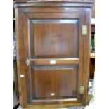 A 19th century oak hanging corner cupboard enclosed by a panelled door