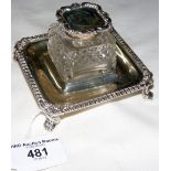 A glass inkwell with silver stand and hinged lid and mount