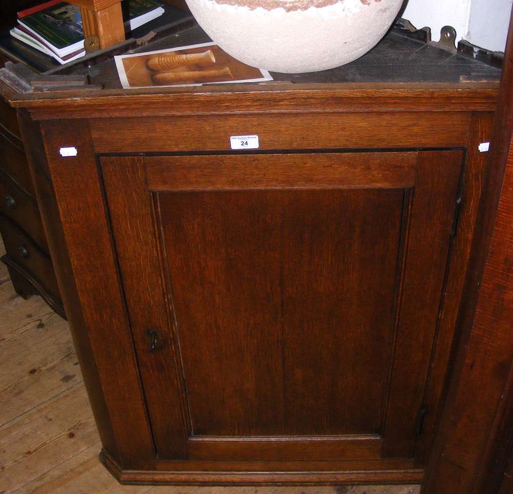 A 19th century oak hanging corner cabinet enclosed by a panelled door