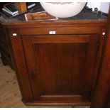 A 19th century oak hanging corner cabinet enclosed by a panelled door