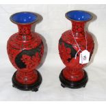 A pair of oriental red lacquer vases on wooden stands - 24cm high