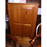 A pine two door wardrobe with drawer to the base