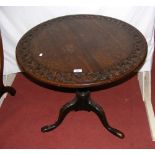 An antique snap-top table with carved circular top