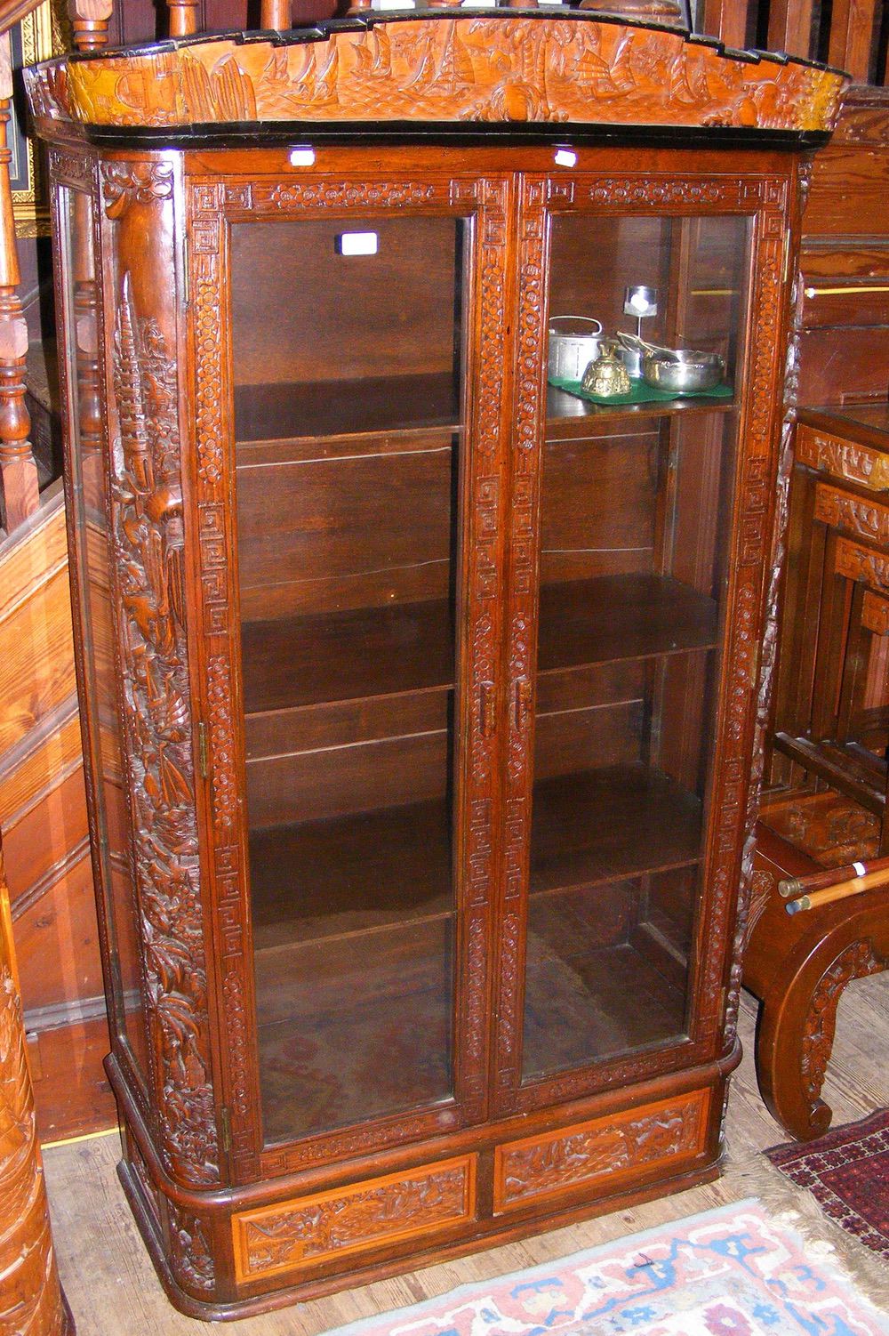 A carved oriental two door display cabinet with two drawers to the base - 164cm high x 90cm wide