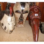 A carved wooden tribal mask with painted decoration, together with two others