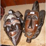 A carved wooden tribal mask, together with one other