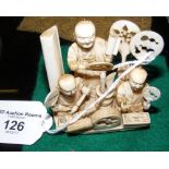 A carved ivory figural group of men in workshop - 6.5cm high