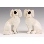 A PAIR OF LATE 19TH CENTURY STAFFORDSHIRE SEATED POODLE DOGS with partly encrusted white glazed