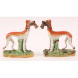 A PAIR OF LATE 19TH CENTURY STAFFORDSHIRE HOUNDS Modelled standing on stumpwork bases with hares
