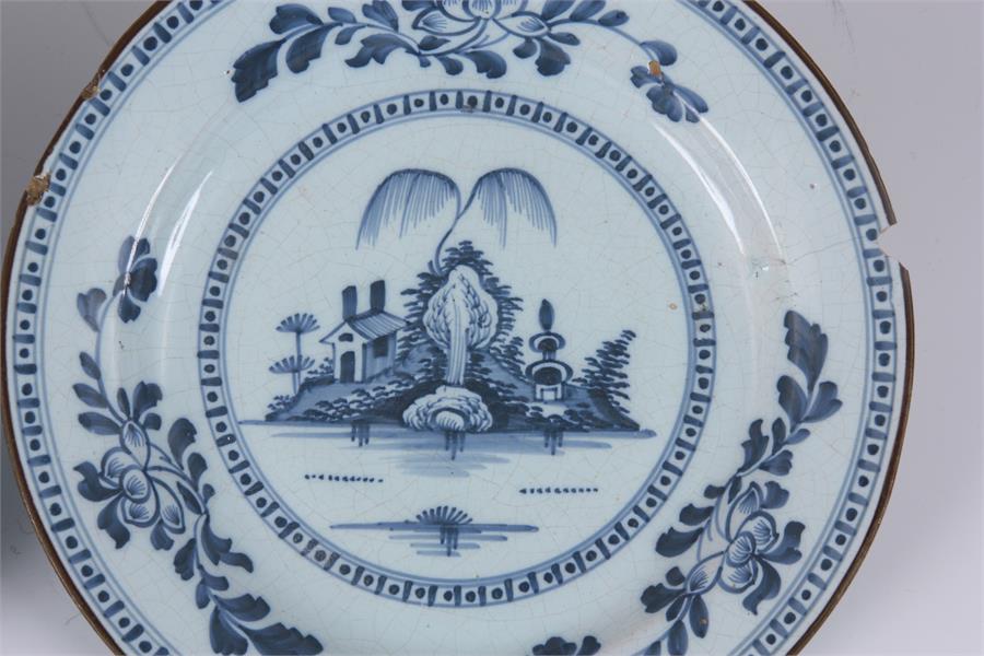 A PAIR OF 18TH CENTURY ENGLISH BLUE AND WHITE DELFT PLATES with landscape centres and leafing flower - Image 3 of 10