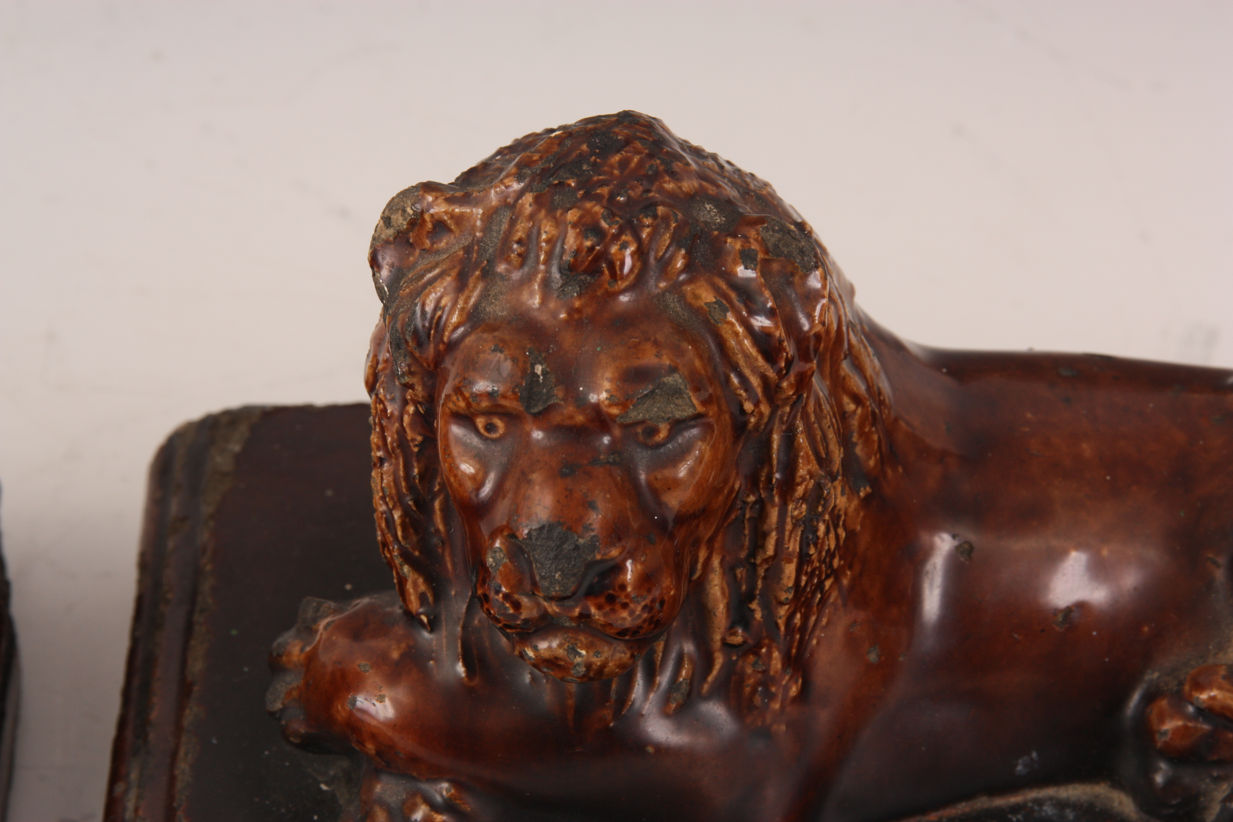 A PAIR OF 19TH CENTURY TREACLE GLAZED STAFFORDSHIRE RECUMBENT LIONS on moulded plinth bases 25cm - Image 4 of 5