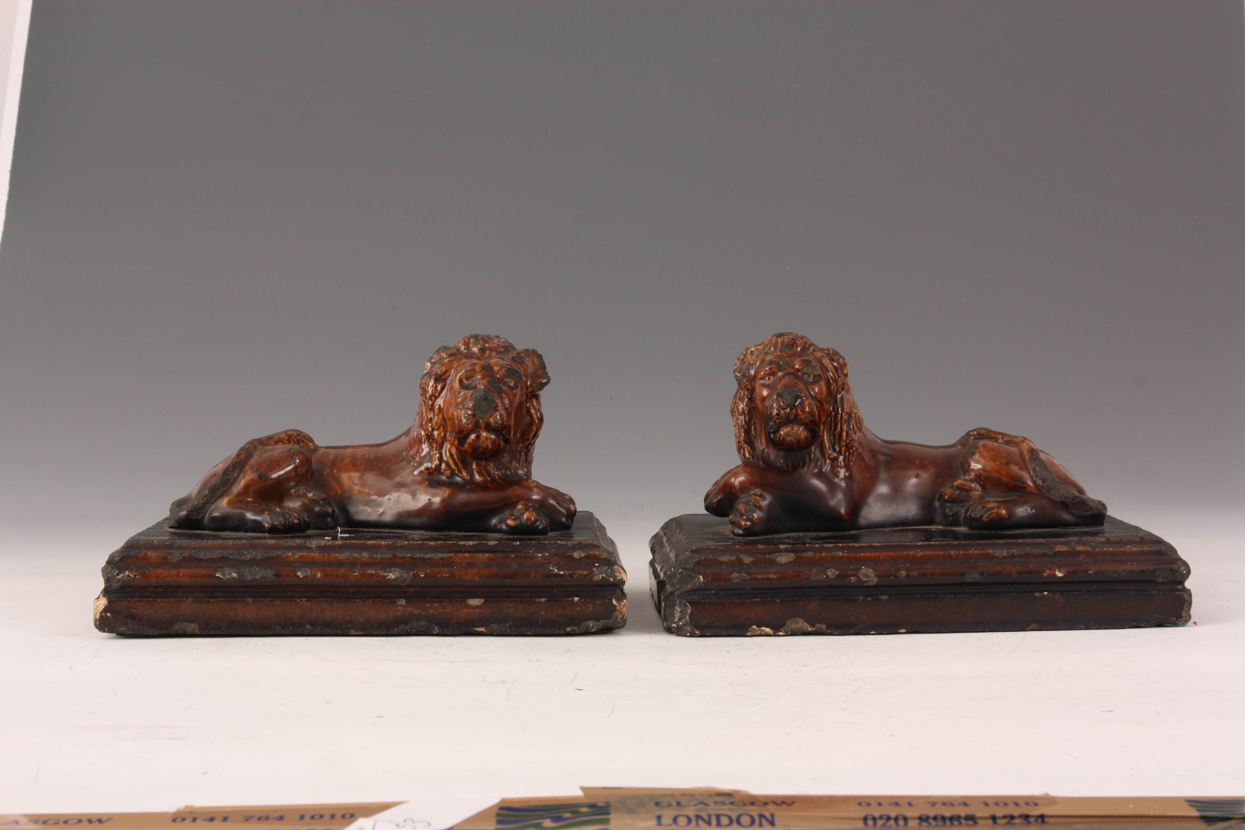 A PAIR OF 19TH CENTURY TREACLE GLAZED STAFFORDSHIRE RECUMBENT LIONS on moulded plinth bases 25cm - Image 3 of 5