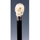 A EARLY 20TH CENTURY EBONISED WALKING STICK with silver collar and bone carved Skull handle 92cm